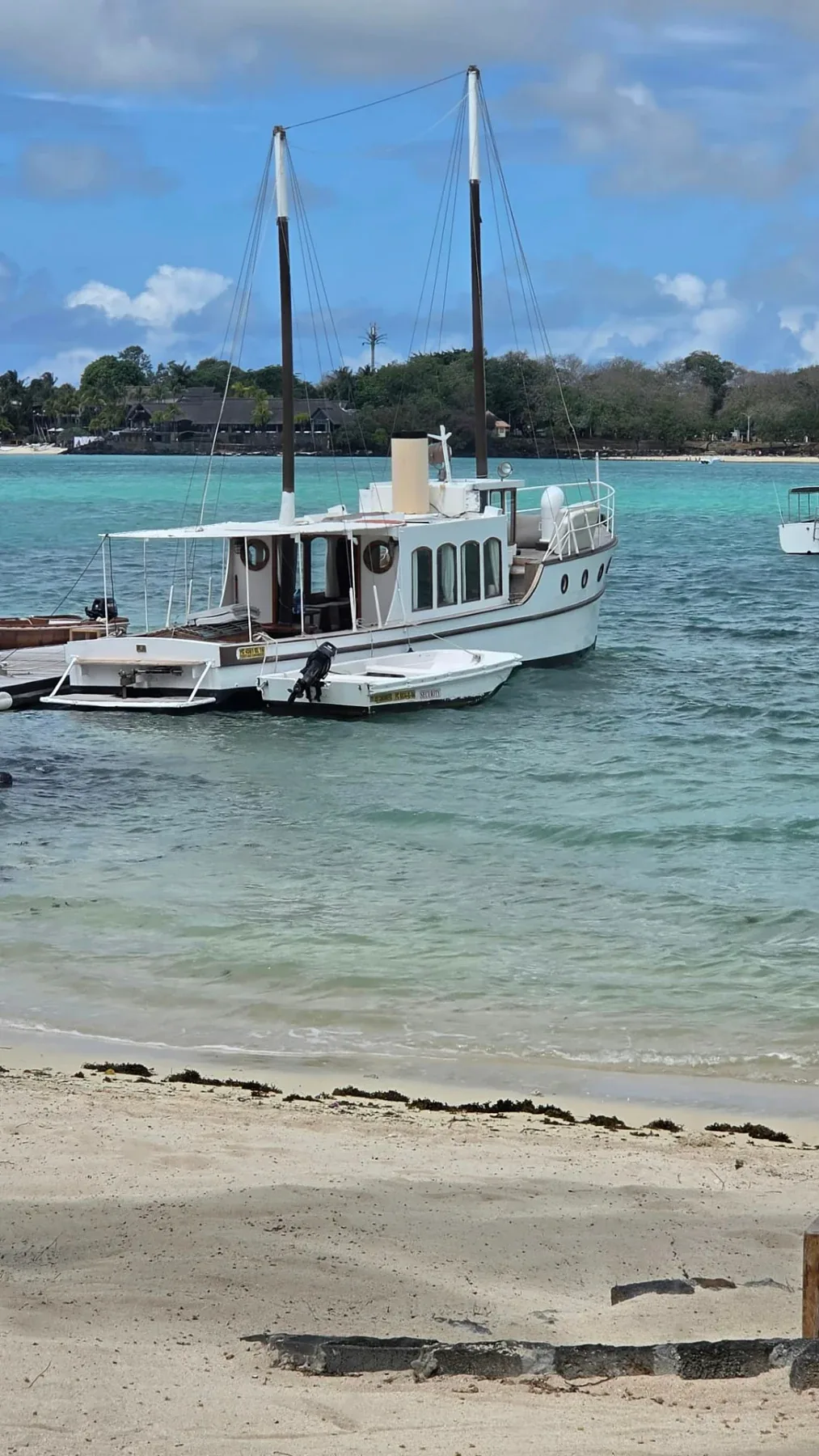 Vit segelbåt vid en strand med turkost vatten och palmer på Mauritius