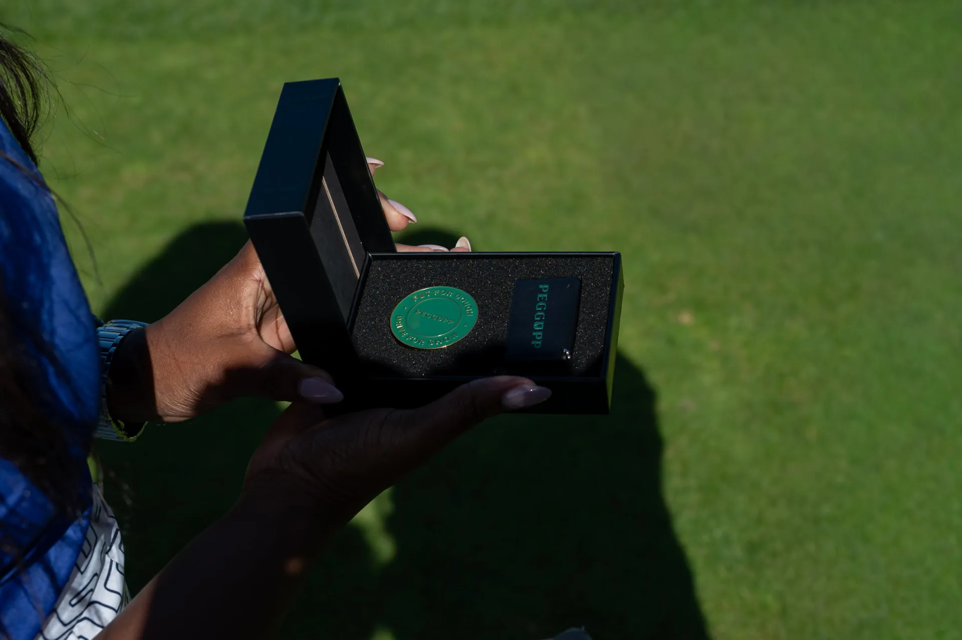 PEGGUPP-bollmarkör och kort i en öppen ask på golfbanan